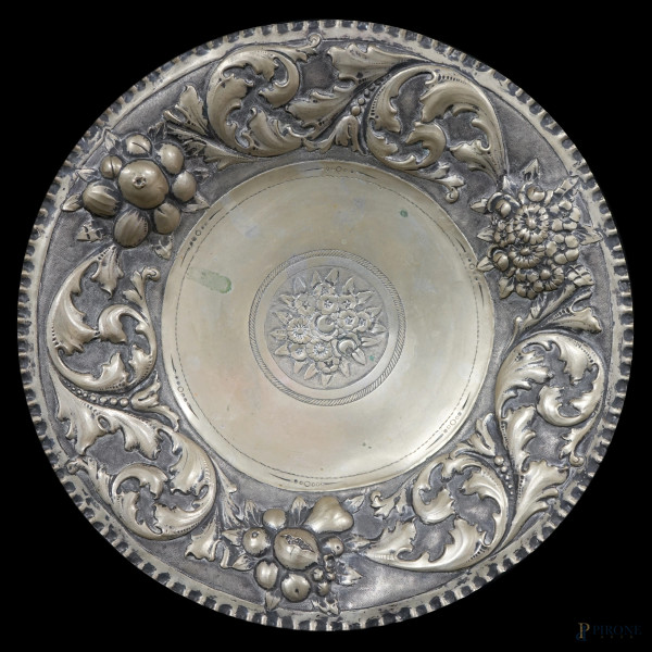 Centrotavola in argento sbalzato e cesellato, cavetto con decori floreali incisi, tesa decorata a motivi vegetali, punzoni sotto la base, cm 35,5x6, peso gr. 864, (difetti)