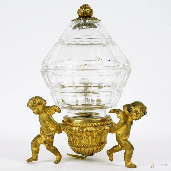 Lampada in cristallo, poggiante su base sorretta da tre putti in metallo dorato,  cm h 16,5, XX secolo, (difetti),