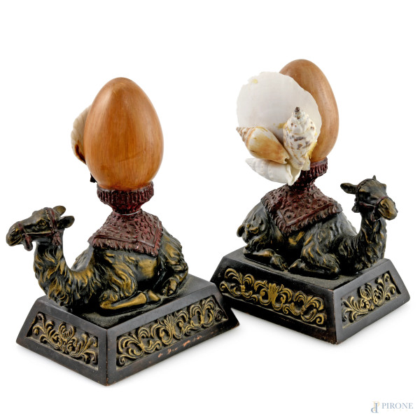 Coppia di sculture in resina dipinta a guisa di dromedario con elemento apicale a foggia di uovo in pietra dipinta e conchiglie applicate, XX secolo, altezza massima cm 18, (segni di usura, difetti)