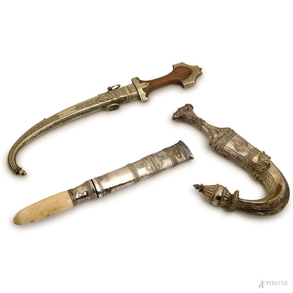 Lotto di tre modelli di scimitarre e coltello berberi rivestite in lamina di argento e metallo argentato, XX secolo, misure massime cm 42 (difetti)