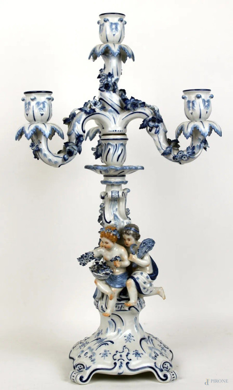 Candelabro a tre luci in porcellana Meissen bianco e blu, fusto centrale con gruppo allegorico raffigurante la Primavera e l'Estate, bracci portacandela a volute, bobèches modellate a forma di corolla, base quadrilobata con piedini desinenti a ricciolo, altezza cm 50, XX secolo  - Asta PRIMA TORNATA D' ASTA A TEMPO DI FINE STAGIONE - Aste Pirone