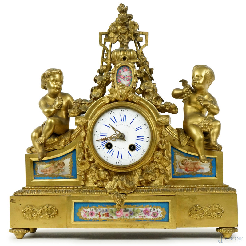 Orologio da tavolo Raingo Fres Paris, XIX secolo, in bronzo dorato sormontato da vaso con fiori ricadenti e putti ai lati, quadrante circolare a numeri romani, placche in porcellana Sevres decorate a fiori e cherubini, cm 33x30x10  - Asta ASTA DI ANTIQUARIATO - Aste Pirone